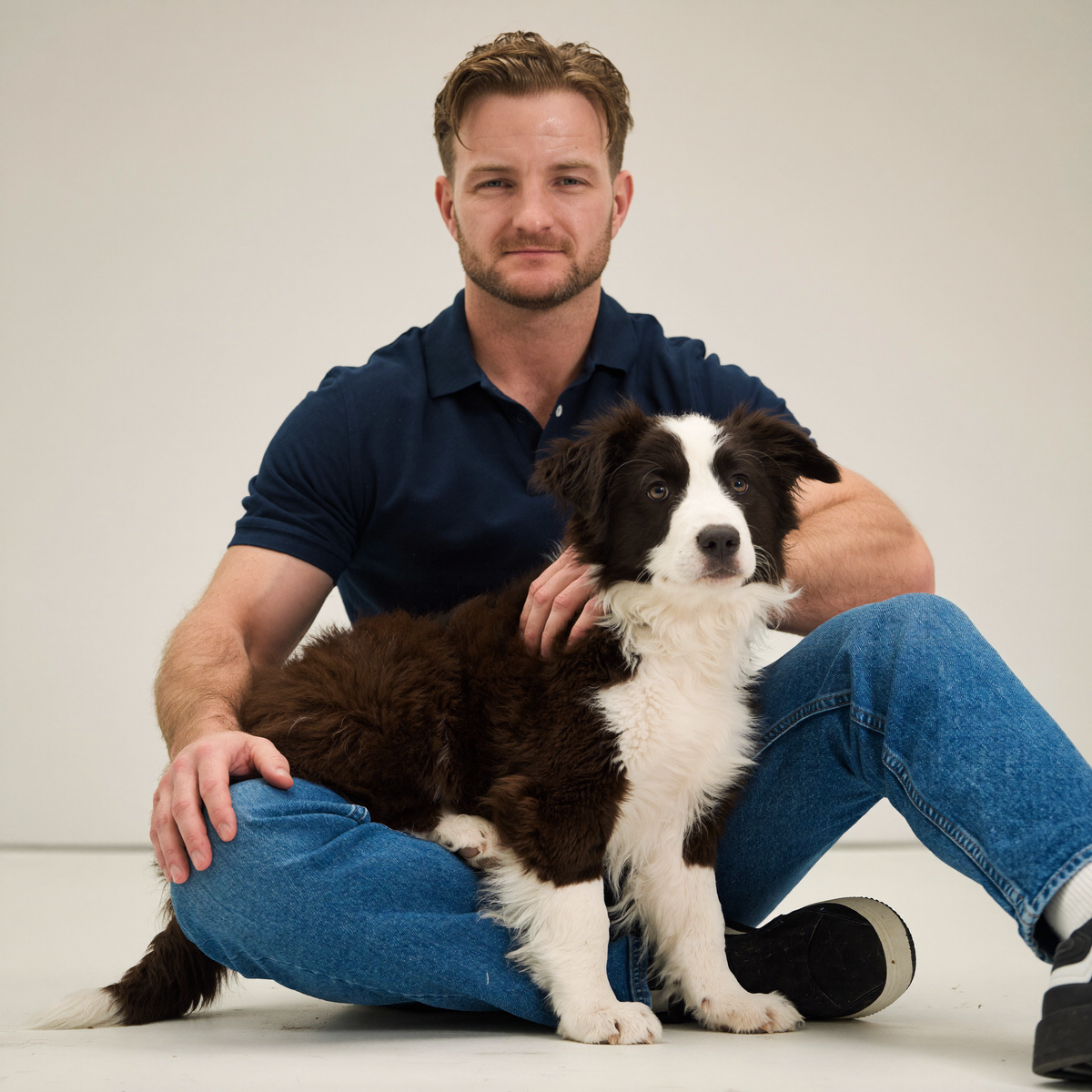 Border Collie puppy sitting in the lap of Sydney dog trainer Luke Buchanan